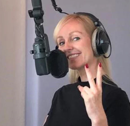Sprecherin Jennifer Long steht am Mikrofon und macht das Peace-Zeichen